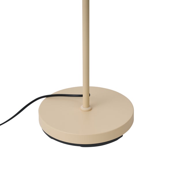 Runder Lampenfuß einer Stehlampe aus Metall in Sandfarben mit schwarzem Kabel.