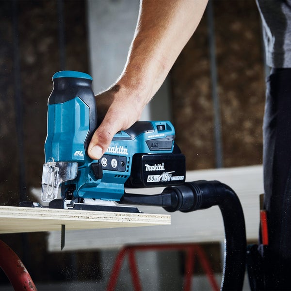 Makita Logo. Akku-Stichsäge im Einsatz beim Sägen von Holz