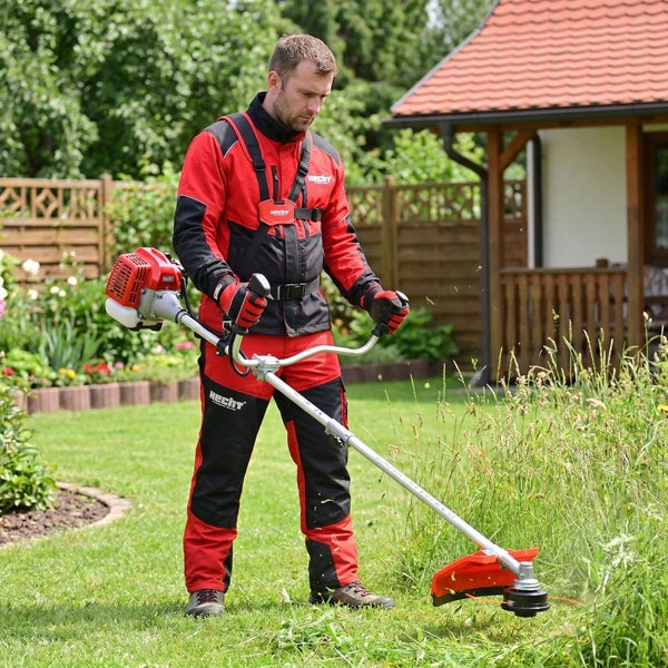 Mann schneidet Gras mit einem Freischneider im Garten