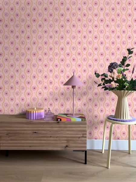 Dekoratives Zimmer mit gemusterten Tapeten, Kommode und Blumenarrangement.