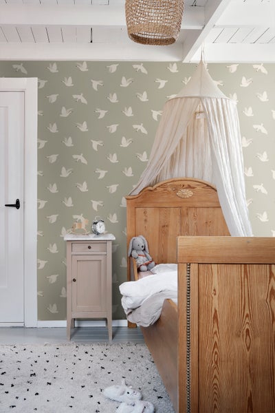 Kinderzimmer mit Holzbett, Nachttisch und Tapete mit Vogelmuster