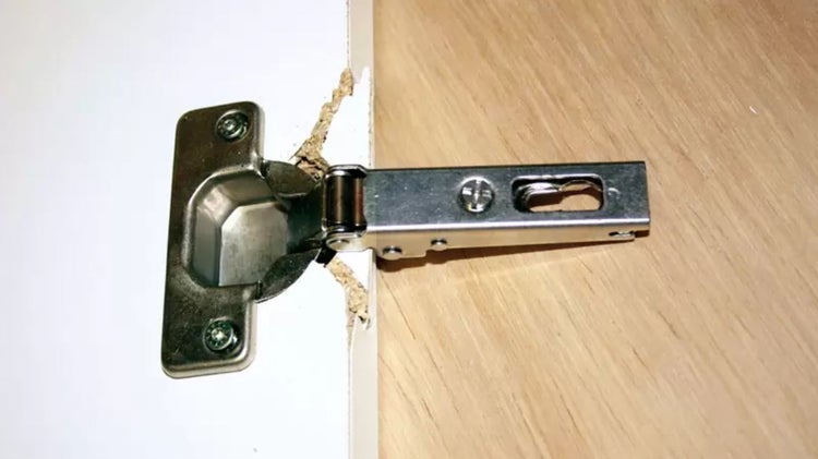 Möbelscharnier an einer beschädigten Schranktür