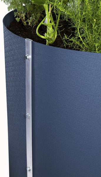 Detailaufnahme eines Hochbeets aus Metall mit strukturierter Oberfläche, Aluminium-Eckleiste mit Schrauben und grünen Pflanzen in Erde.