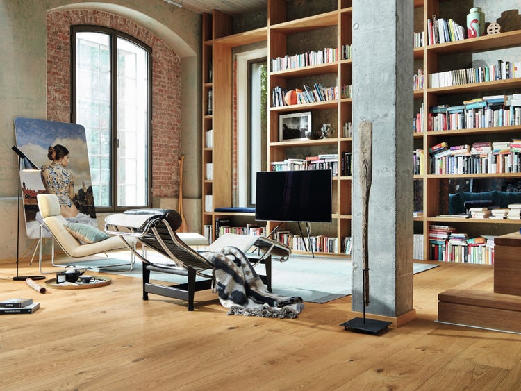 Modernes Wohnzimmer im Loft-Stil mit Eichenparkett, großem Holzregal, Betonpfeiler, Liegesesseln und großen Fenstern mit Ziegelsteinbögen.