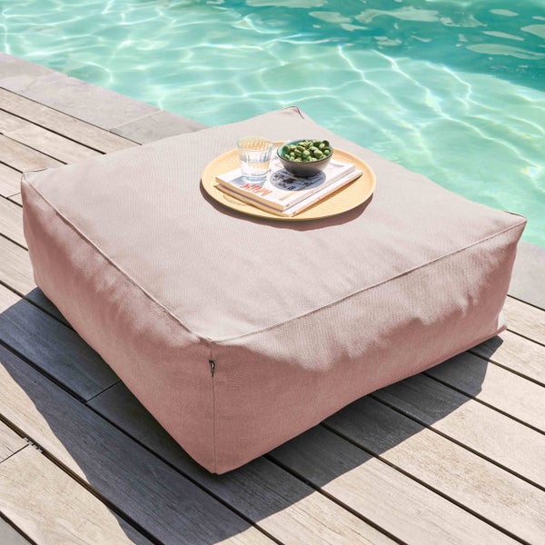 Quadratischer Outdoor-Sitzsack aus strukturiertem Stoff auf einer Holzterrasse neben einem Swimmingpool.