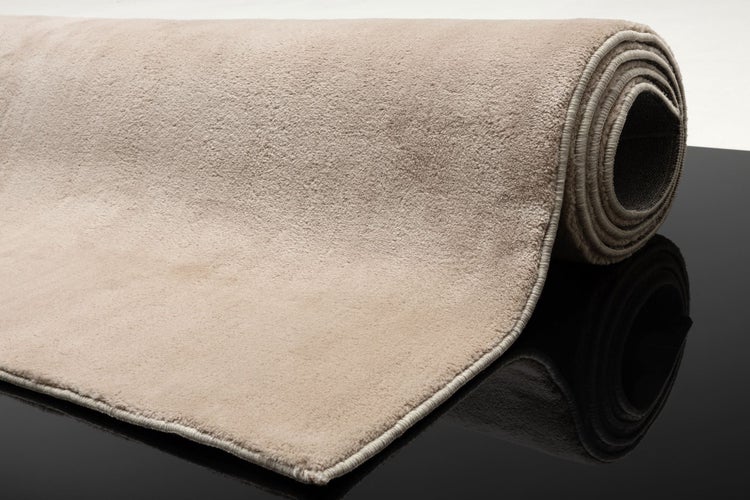 Weicher kurzfloriger Teppich beige teilweise aufgerollt mit sauber verarbeiteter Kettelkante