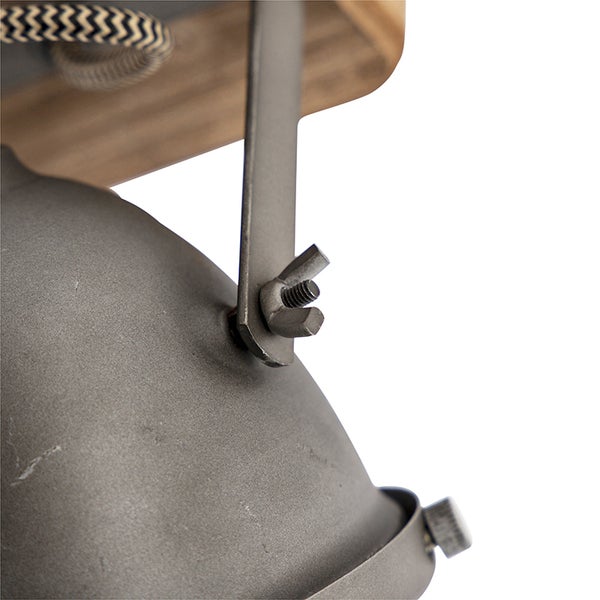 Detailaufnahme einer Deckenleuchte mit Metallscheinwerfer und Holzsockel