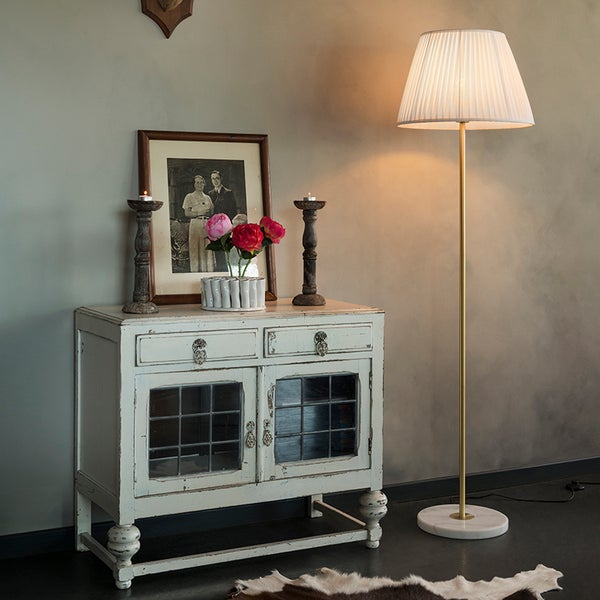 Szene mit einer Kommode, Dekoration und einer Stehlampe.