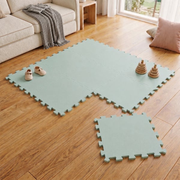 Modulare Spielmatte als Puzzlematte für Kinderzimmer auf Holzboden mit Spielzeug und Kinderschuhen
