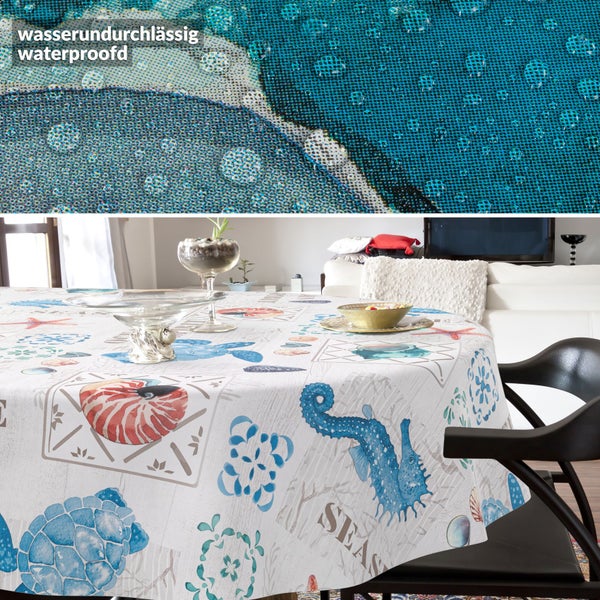 Wasserundurchlässige Tischdecke mit maritimem Muster wie Seepferdchen und Muscheln auf einem gedeckten Tisch. Detailaufnahme von Wassertropfen.
