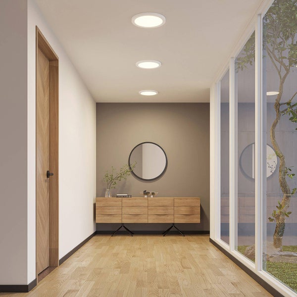 Moderner, heller Flur mit drei runden LED-Deckenleuchten, Sideboard aus Holz, rundem Spiegel und einer Holztür. Minimalistisches Design.