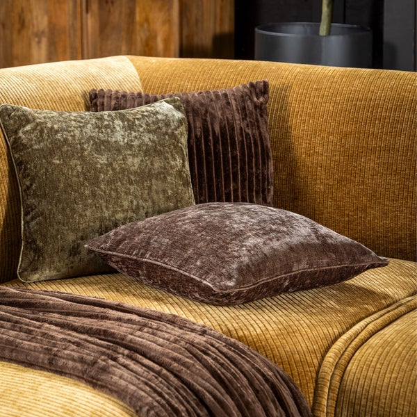 Ein Sofa aus Cordstoff mit verschiedenen Zierkissen aus Samt und Cord in einem gemütlichen Wohnbereich.