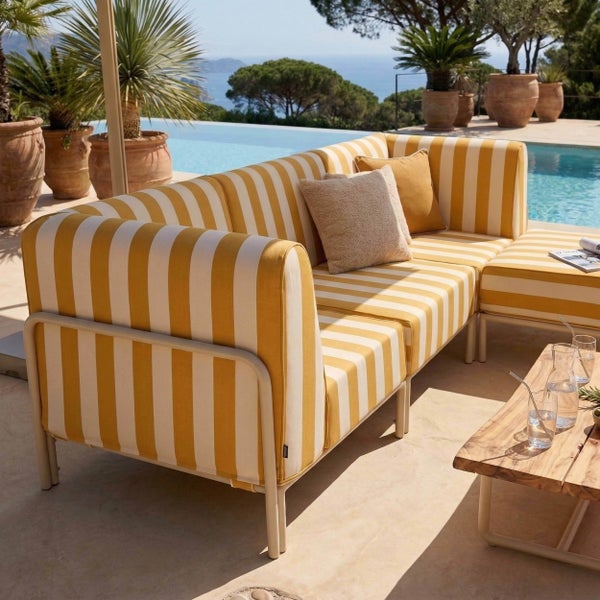 Moderne Gartenlounge mit gelb-weiß gestreiften Polstern auf Metallgestell auf einer hellen Terrasse am Pool mit Palmen.