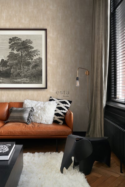 Wohnzimmer mit Ledersofa, Kissen, Teppich und Wandbild