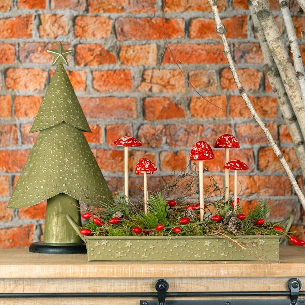Weihnachtliche Tischdekoration mit Metalltannenbaum und künstlichen Pilzen auf einem rechteckigen Metalltablett mit Sternenmuster.