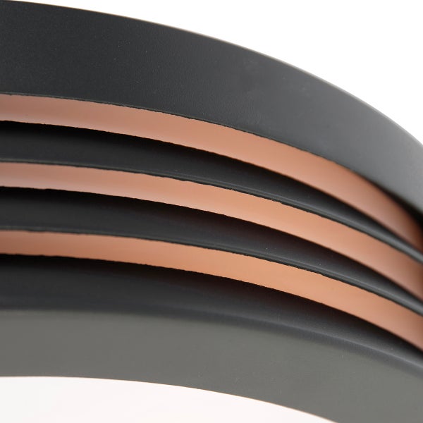 Detailansicht einer modernen Leuchte mit geschwungenen, mattschwarzen Ringen und holzfarbener Innenseite.