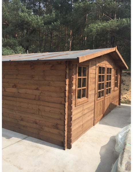Geräumiges Gartenhaus aus Holz in Blockbohlenbauweise mit Satteldach, Doppeltür und Sprossenfenstern auf hellem Untergrund vor einem Wald.