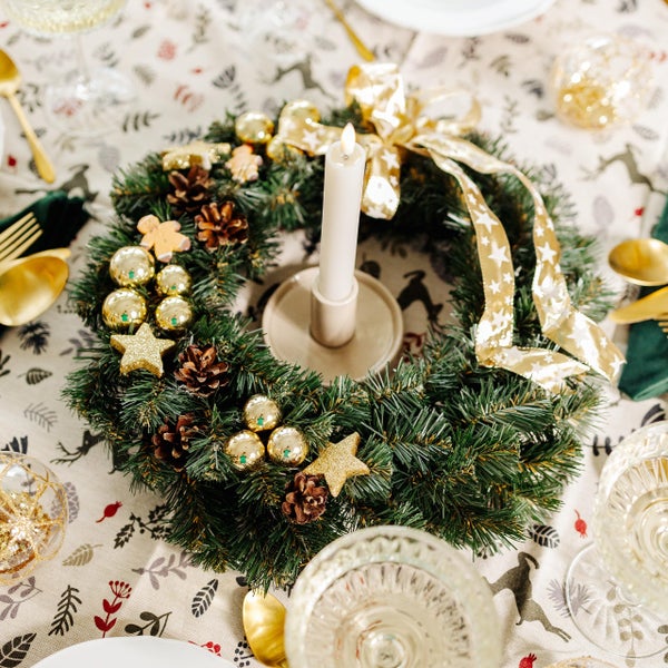 Künstlicher Weihnachtskranz mit goldener Schleife, Kugeln, Glitzersternen, Tannenzapfen und Lebkuchenmännchen.