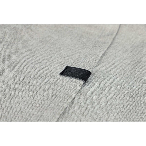 Nahaufnahme eines hellgrauen Stoffes mit einem kleinen, dunklen Etikett