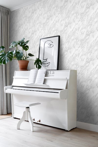 Heller Raum mit Marmortapete, weißem Klavier, Hocker, Zimmerpflanze und gerahmtem Bild
