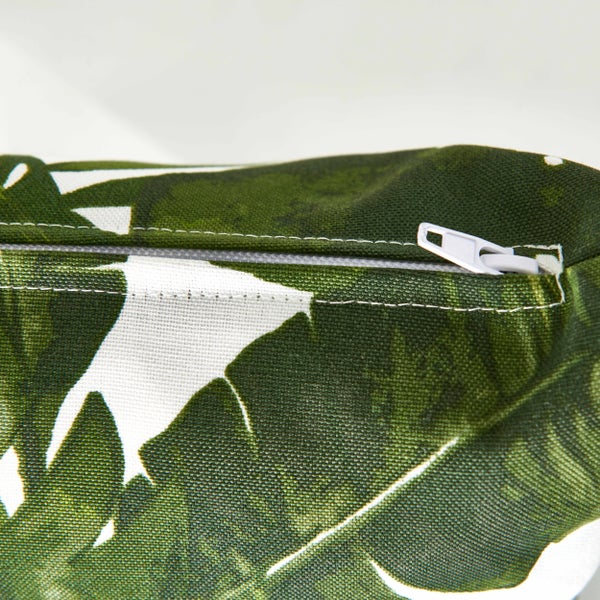 Detail eines Kissenbezugs mit Reißverschluss und grünem Blattmuster.