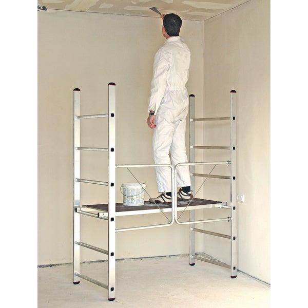 Handwerker auf einem Aluminium-Arbeitsgerüst spachtelt die Zimmerdecke.