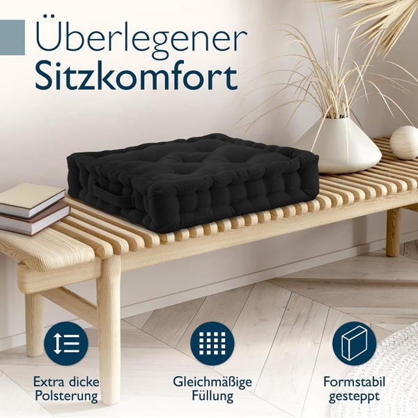 Schwarzes extra dickes gestepptes Sitzkissen mit Tragegriff auf einer hellen Holzbank.