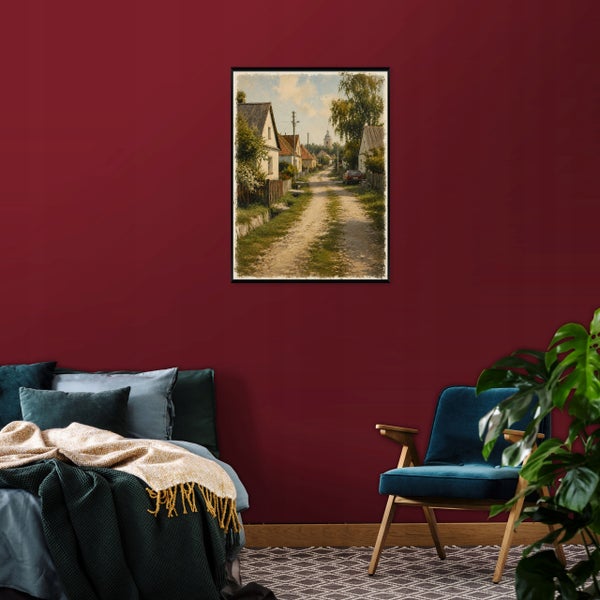 Gerahmtes Wandbild mit einer ländlichen Dorfstraße, hängend über einem Schlafzimmerbett mit Sessel und Zimmerpflanze.