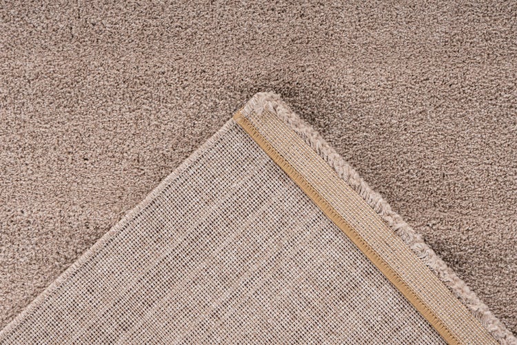 Detailansicht eines Teppichbodens mit strukturierter Floroberfläche und gewebter Gitterrückseite mit Abschlusskante.