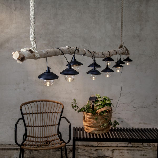 Dekorative Hängelampe mit Holzstamm und mehreren Leuchten über einem Stuhl und einer Bank