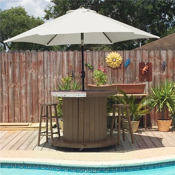 Szene mit einem Bartisch, Hockern und einem Sonnenschirm am Pool