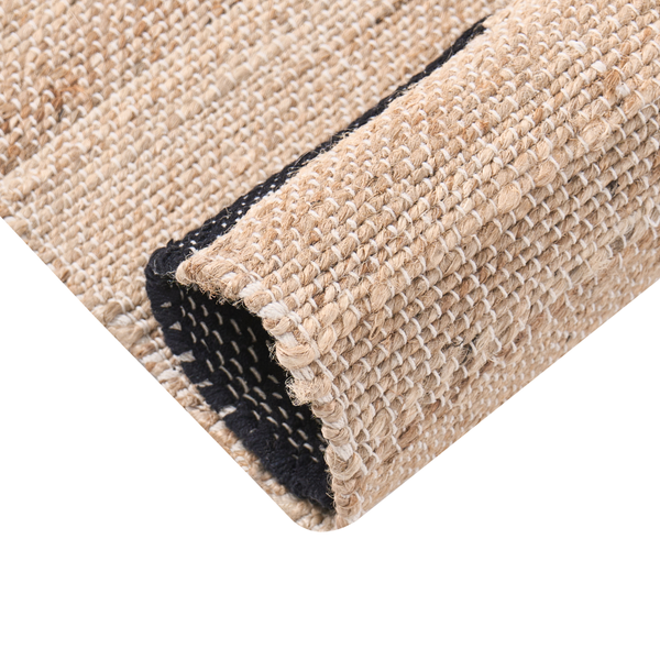 Detail eines handgewebten Jute-Teppichs mit grober Struktur und schwarzer Kante.