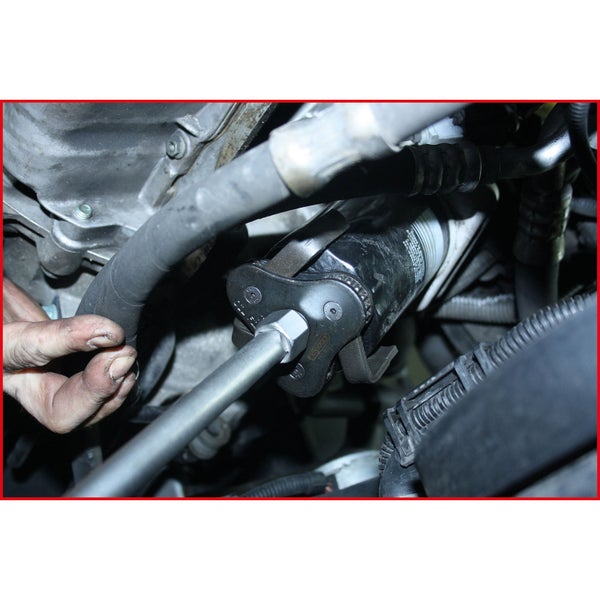 Ölfilterschlüssel im Einsatz an einem Motor.