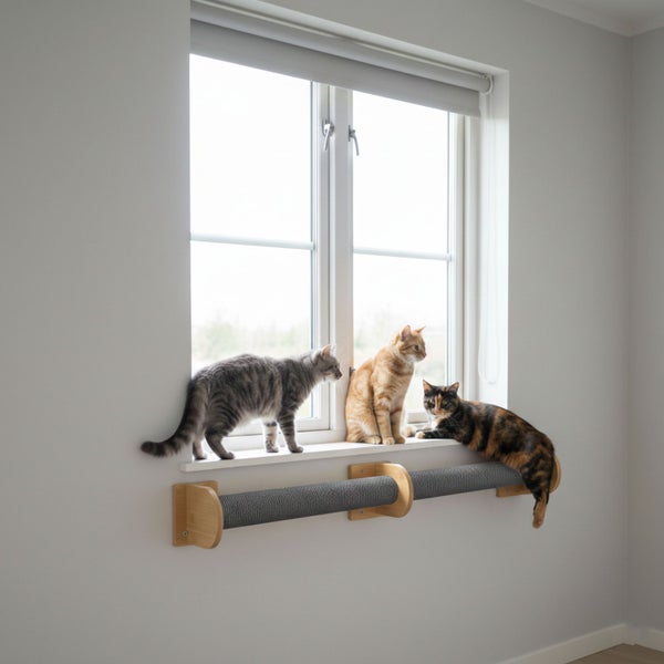 Drei Katzen sitzen auf einem Fensterbrett über einem hölzernen Kratzstamm mit grauer Sisaloberfläche zur Wandmontage unter dem Fenster.