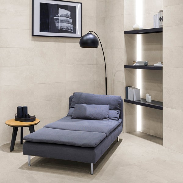 Moderne Lounge mit Liegesessel, Beistelltisch und Wandregalen vor hell gefliesten Wänden in einem Wohnraum.