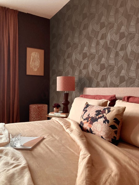 Schlafzimmer mit Bett, Nachttischlampe und gemusterter Tapete