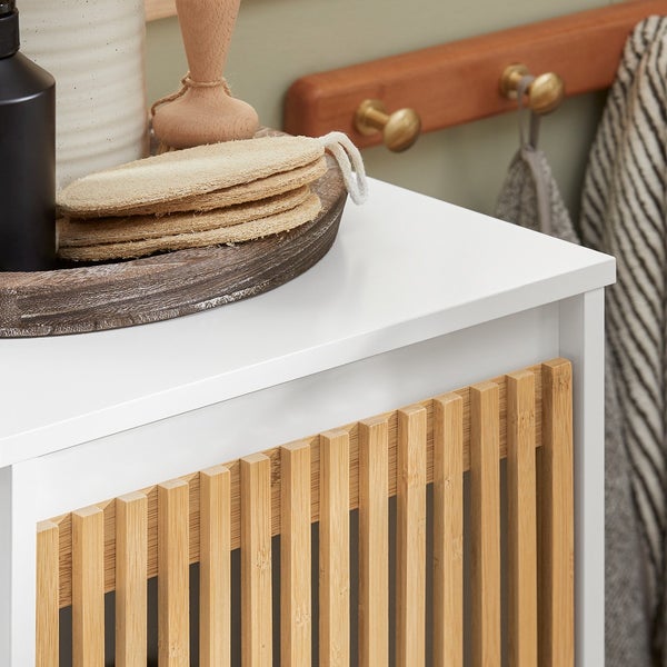 Detailansicht eines weißen Badezimmerschranks mit hölzernen Lamellentüren.