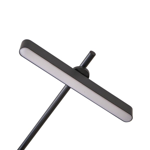 Schlafzimmer mit Bett, Nachttischlampe und Wandtapete in Holzoptik.