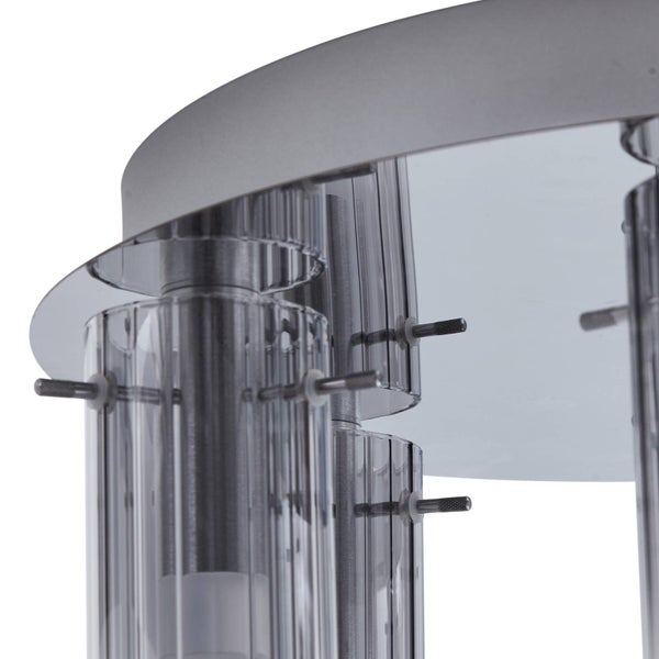 Detailaufnahme einer Deckenleuchte mit silberner Metallbasis und geriffelten Glaszylindern, die mit Metallstiften befestigt sind.