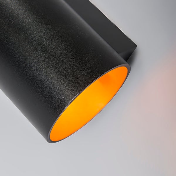 Nahaufnahme einer schwarzen Wandleuchte mit zylindrischem Schirm