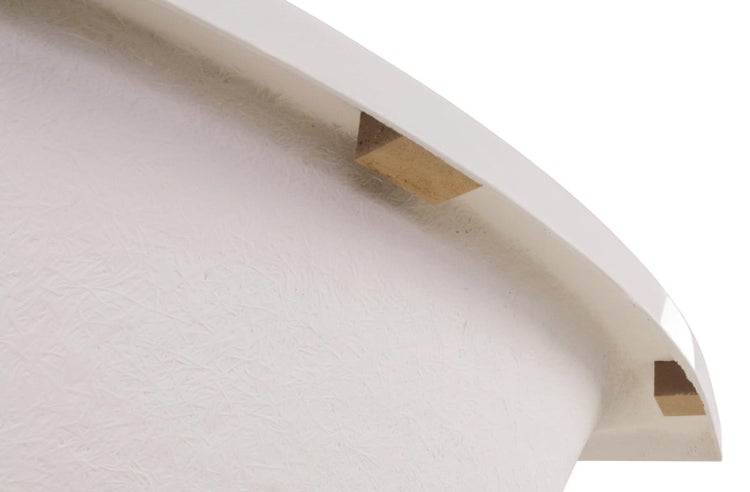 Detailansicht der Unterseite eines Badewannenrandes mit Glasfaserverstärkung und Holzstützblöcken.