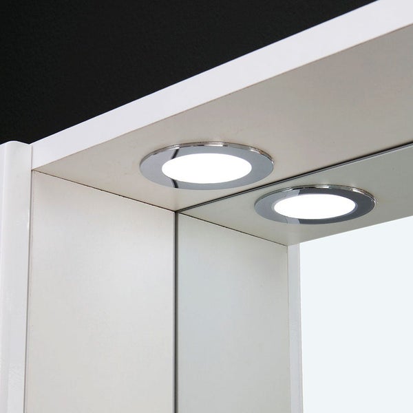 Zwei runde Einbaustrahler mit Chromrand an einem weißen Schrank