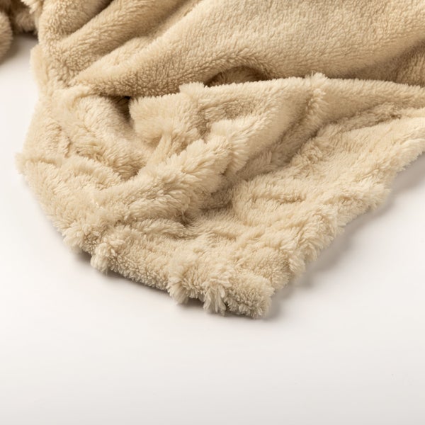 Nahaufnahme einer weichen, flauschigen beigen Wohndecke aus Fleecematerial.