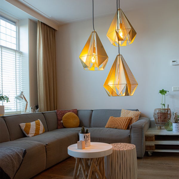Wohnzimmer mit grauer Couch, Couchtisch und drei goldenen Hängelampen im geometrischen Design.
