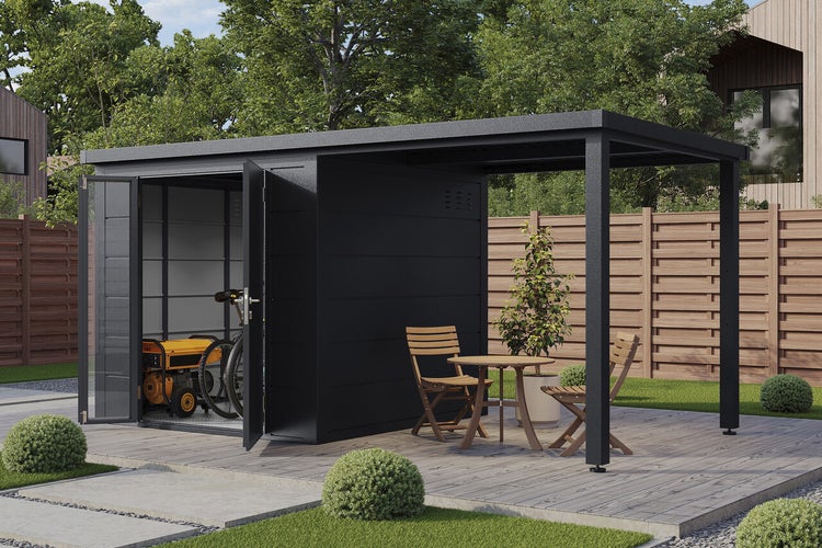 Gerätehaus mit Anbaudach aus Metall in einem Garten mit Sitzgruppe auf der Terrasse stehend.