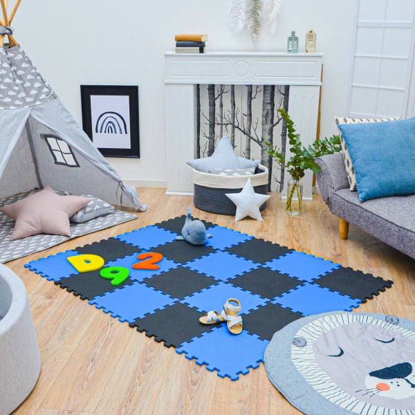 Blau-schwarze Schaumstoff-Puzzlematte in einem hellen, organisierten Spielzimmer mit Tipi, Sofa und Holzboden.