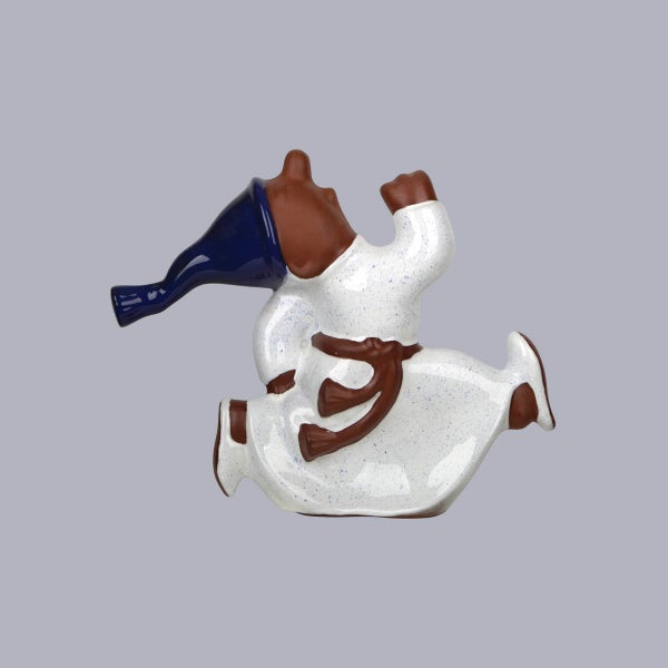 Stilisierte Keramikfigur einer laufenden Gestalt mit blauem, hornförmigem Hut, weißem, gesprenkeltem Gewand und braunen Details.
