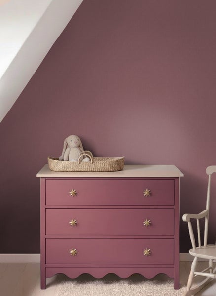 Kinderzimmer mit beerenfarben gestrichener Wand und farblich passender Kommode mit goldenen Sterngriffen.