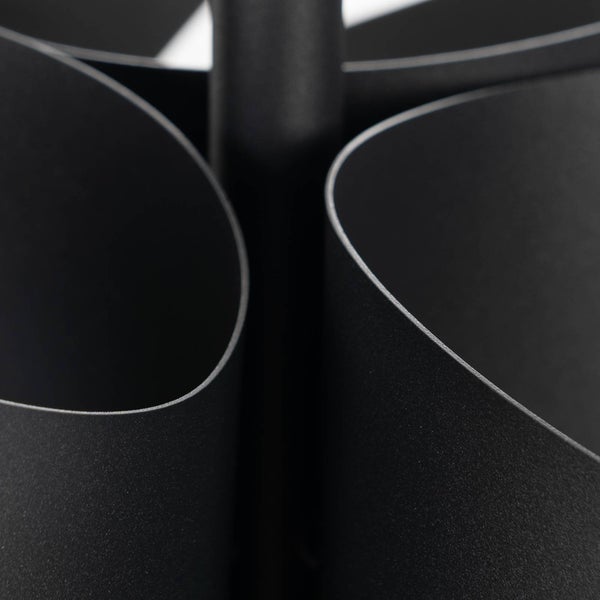 Detailansicht einer schwarzen Leuchte aus Metall mit geschwungenen Formen und matter Oberfläche.