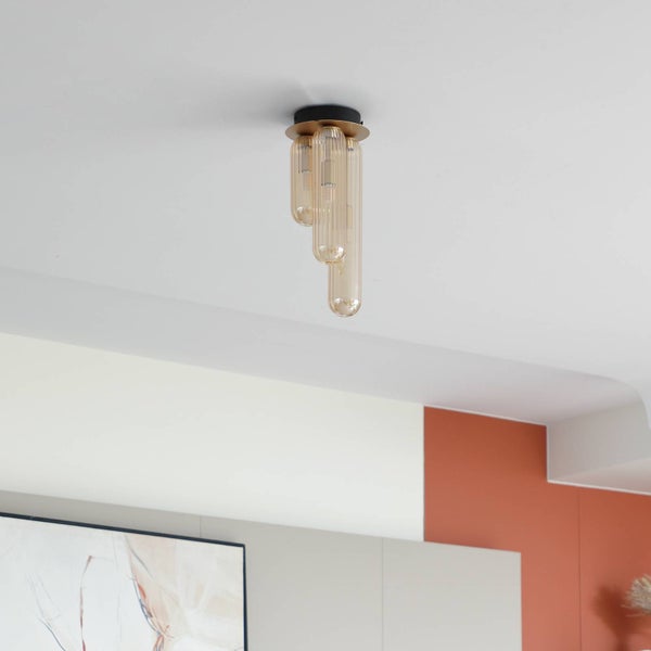 Deckenleuchte mit drei verschieden langen, bernsteinfarbenen Glaszylindern an einer Halterung aus Metall in Schwarz und Messing.